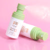 Pixi Skintreats Hydrating Milky Mist Petites bottle shown upright and lying on its side on a pink reflective surface, with mist visible from the pump.