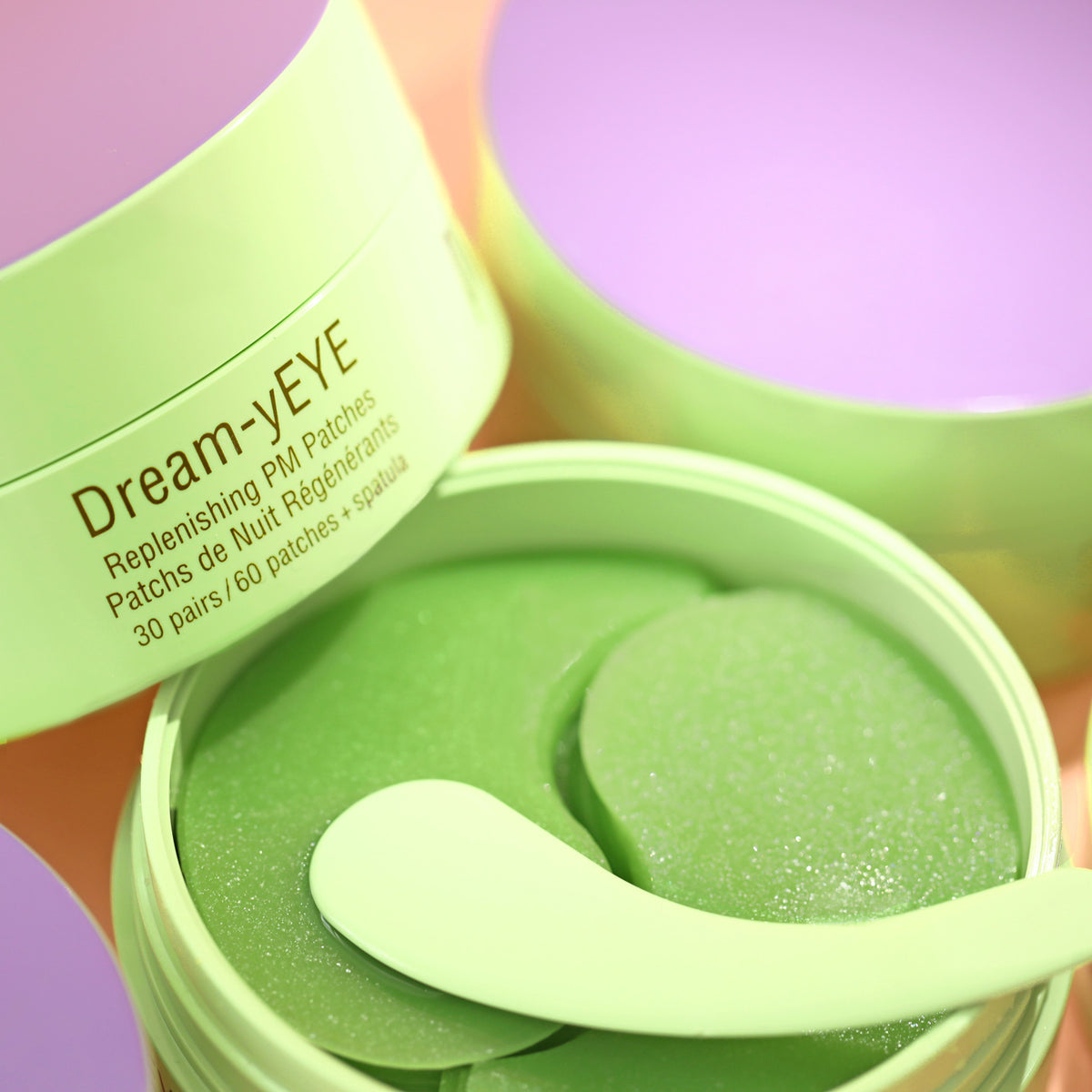 Green container of Dream-yEYE eye patches with an applicator spatula on a colorful background